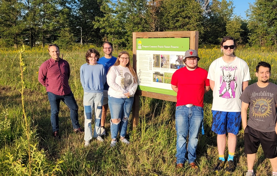 Dr. Burd and students from HIS 4935 stand in front of signage at the Prospect Cemetery Prairie Nature Preserve.